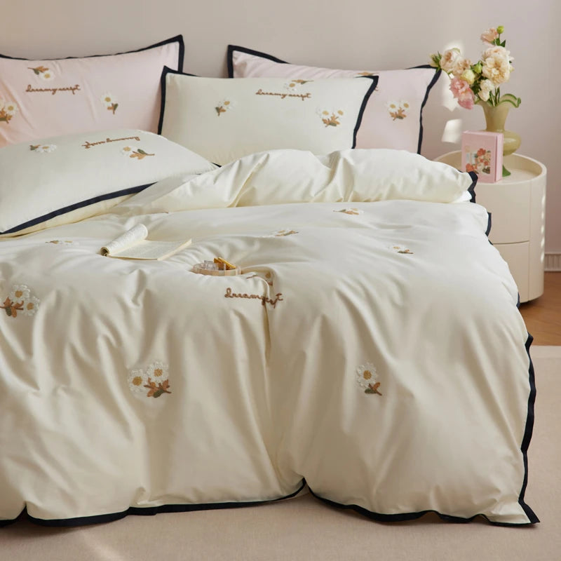Embroidered bedding set with floral designs on a bed in a bedroom setting.