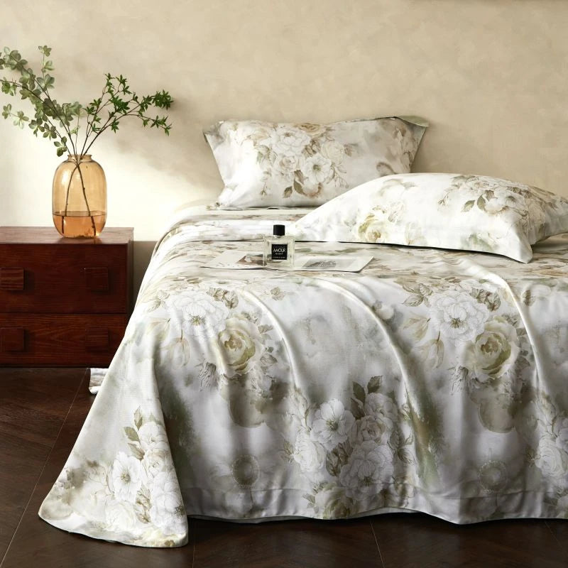 Floral bedding set on a bed with a wooden nightstand and plant in the background.