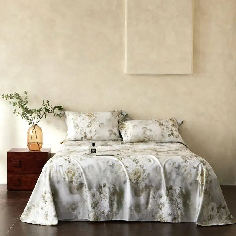 Floral patterned bedsheet on a bed in a bedroom setting with a side table and plant.