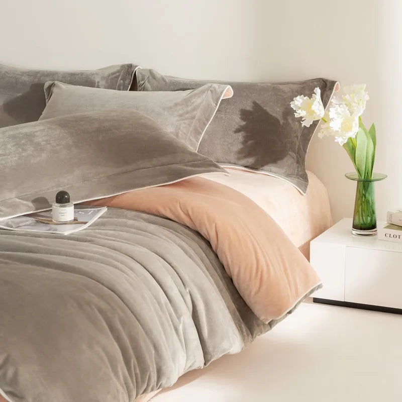 Gray bedding set on a bed with a nightstand and decorative items.