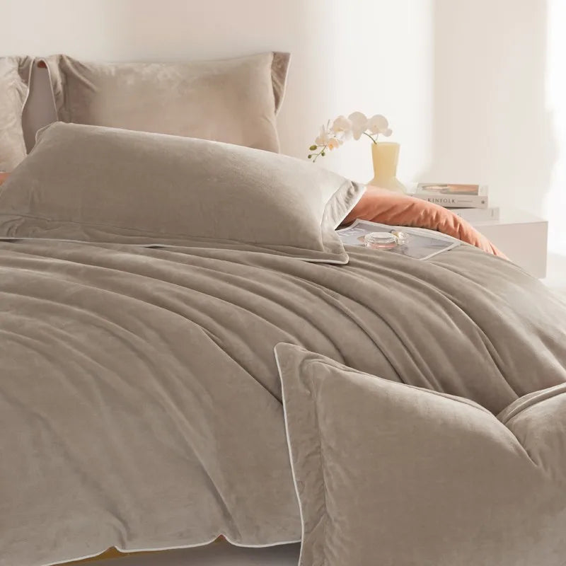 Gray comforter and pillows on a bed with a blurred background