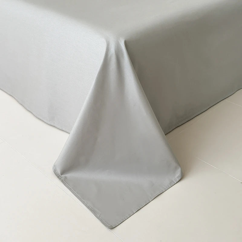 Gray flat sheet on a bed corner with a plain background