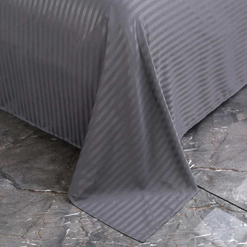 Gray striped bedspread on a bed with a stone floor background