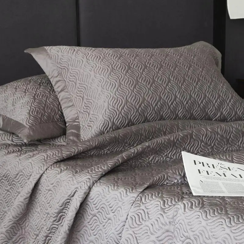 Gray textured bedding set with a newspaper on a bed.