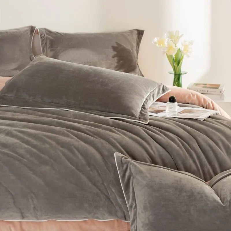 Gray velvet bedding set on a bed with a vase of flowers and books in the background.