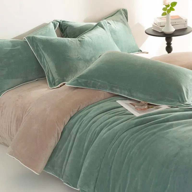 Green and beige velvet bedding set on a bed with a side table in the background.