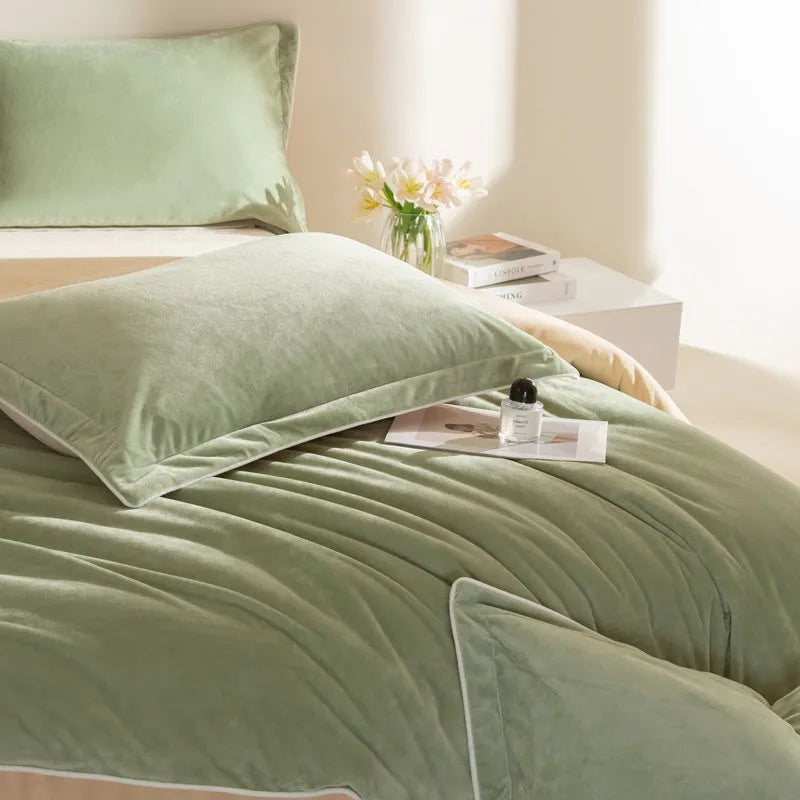 Green reversible  bedding set on a bed with a side table and flowers in the background