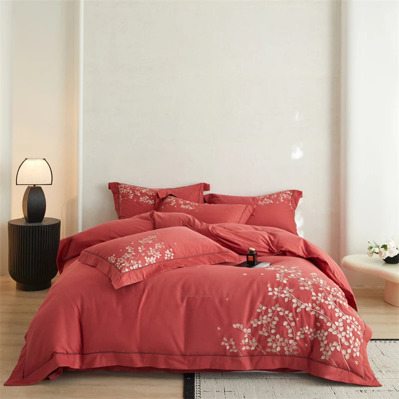 Light Red floral bedding set on a bed in a bedroom with a lamp and decor.