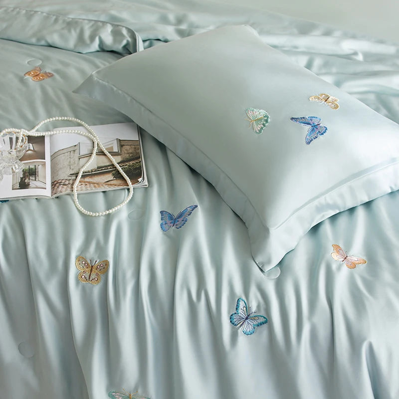 Light blue bedding set with embroidered butterflies on a pillow and duvet.