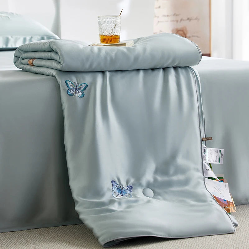 Light blue blanket with butterfly designs on a bed