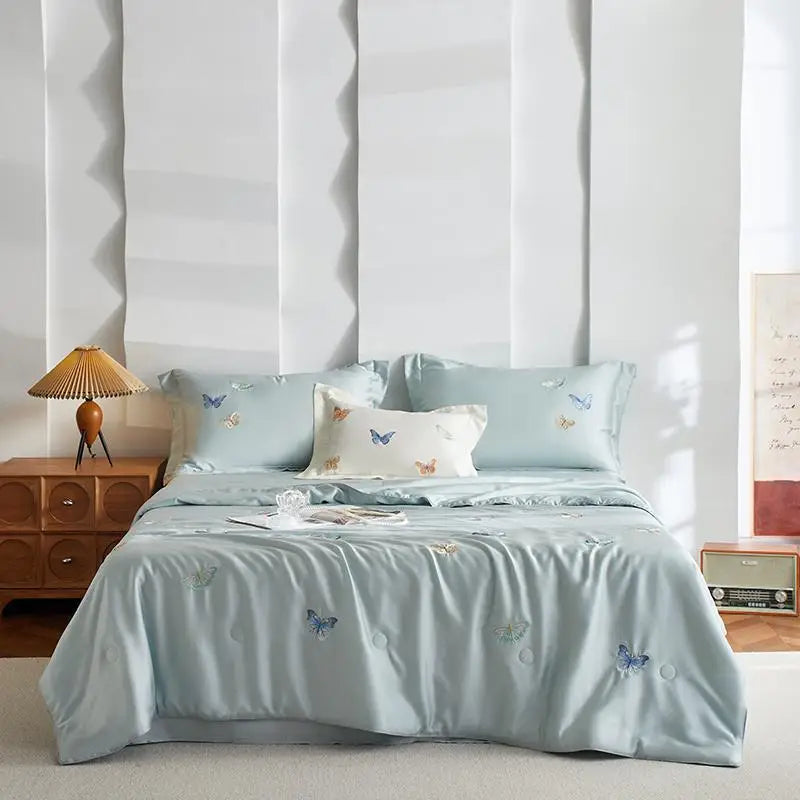 Light blue butterfly-patterned bedding set on a bed in a room.