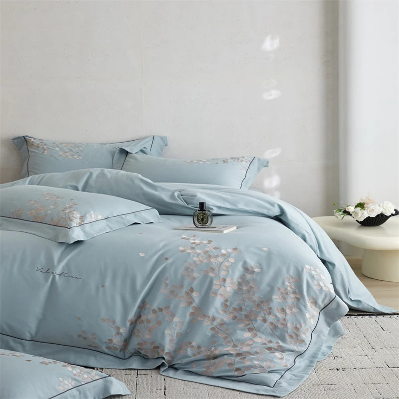 Light blue floral bedding set on a bed in a room with a white wall and light-colored floor.
