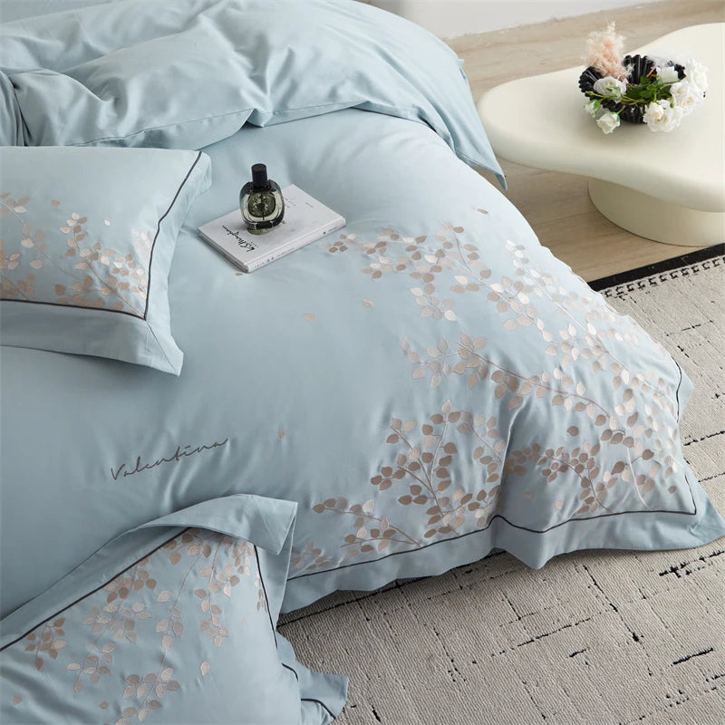 Light blue floral patterned bedding set on a bed with a side table in the background.