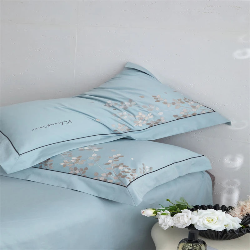 Light blue satin pillowcases with floral embroidery on a white background
