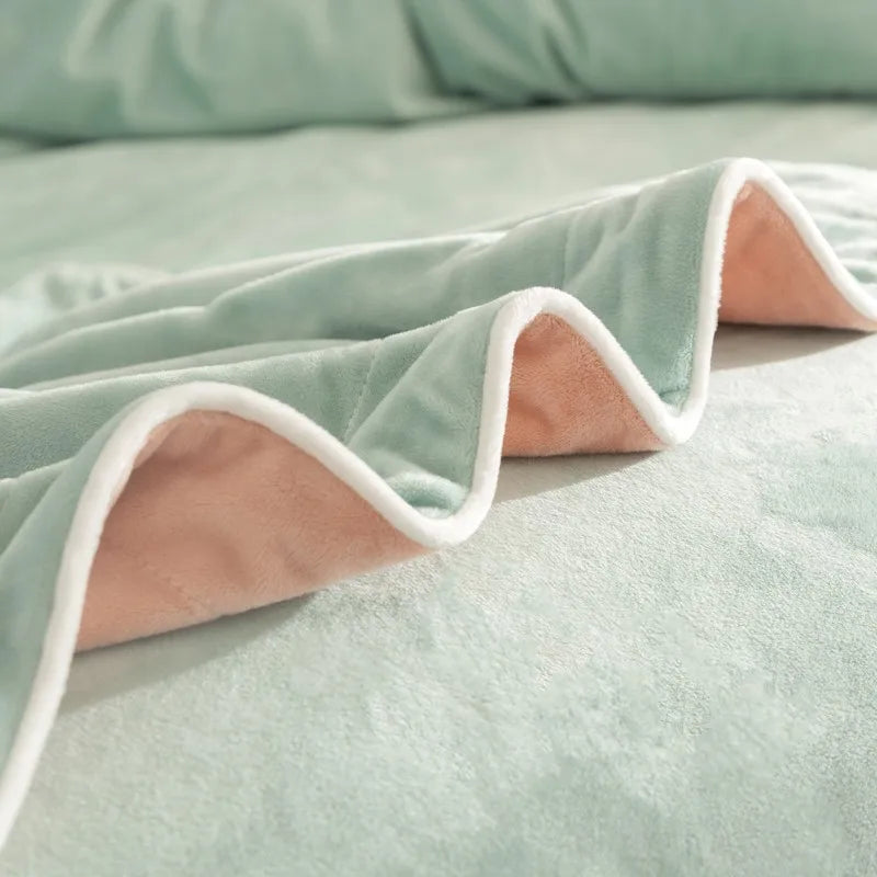 Light green blanket with peach reverse side on a bed