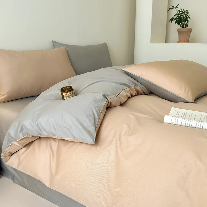 Neatly made bed with beige and gray bedding in a bedroom setting.