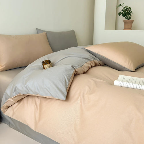 Neatly made bed with beige and gray bedding in a bedroom setting.