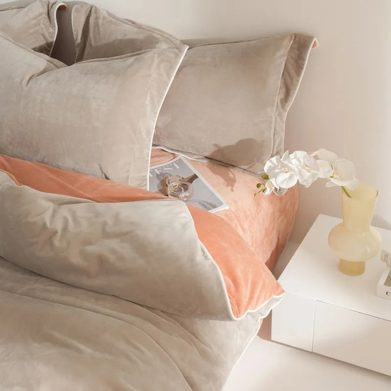 Neatly made bed with beige and peach bedding, nightstand with a vase and flowers.