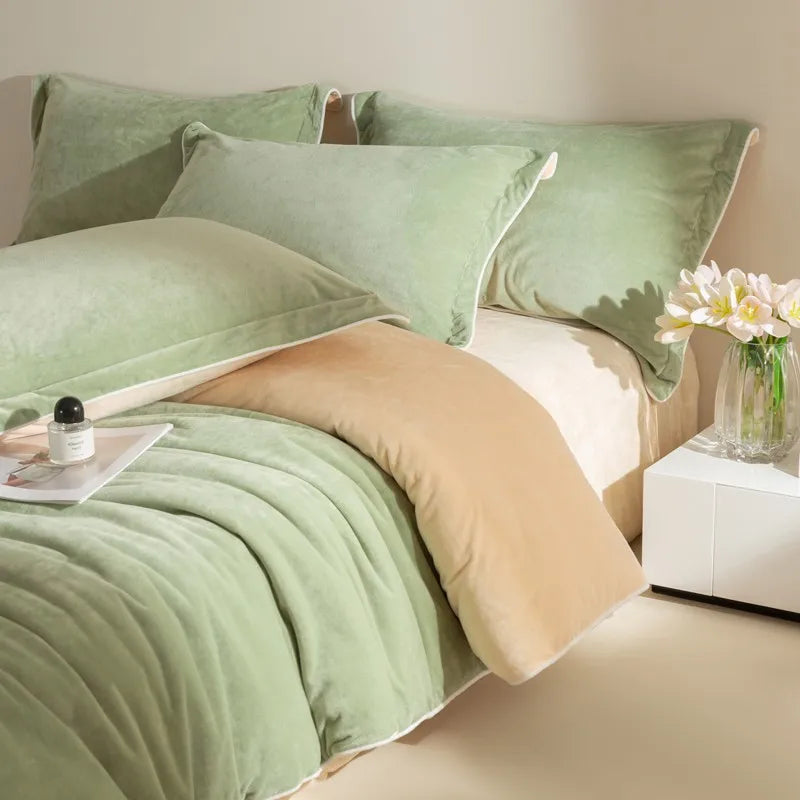 Neatly made bed with green and beige bedding, white nightstand with flowers.