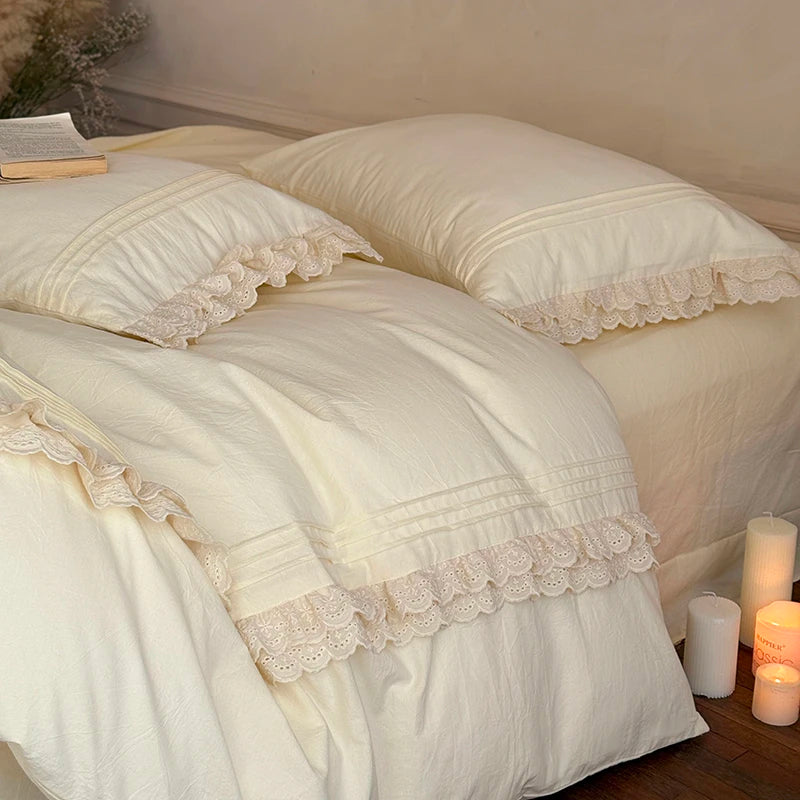 Neatly made bed with lace-trimmed bedding in a softly lit room.