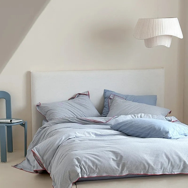 Neatly made bed with light-colored bedding and pillows in a room