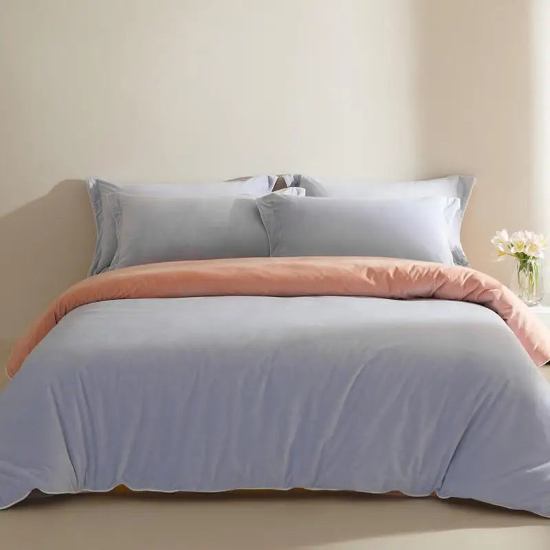 Neatly made bed with light lilac bedding and peach blanket in a bedroom setting.