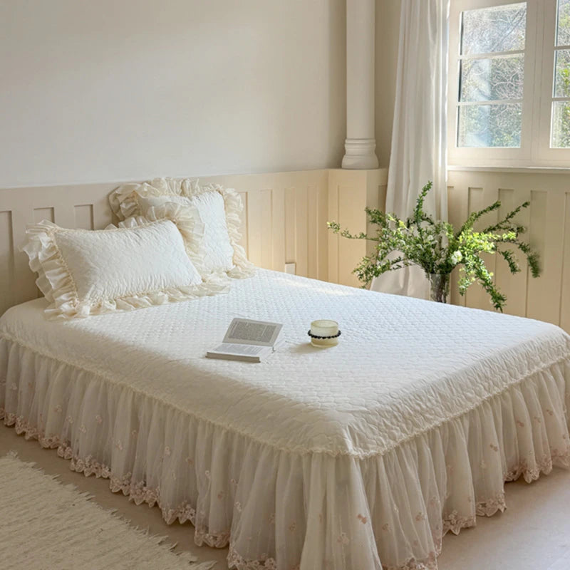 Neatly made bed with white bedding and decorative pillows in a bright bedroom.