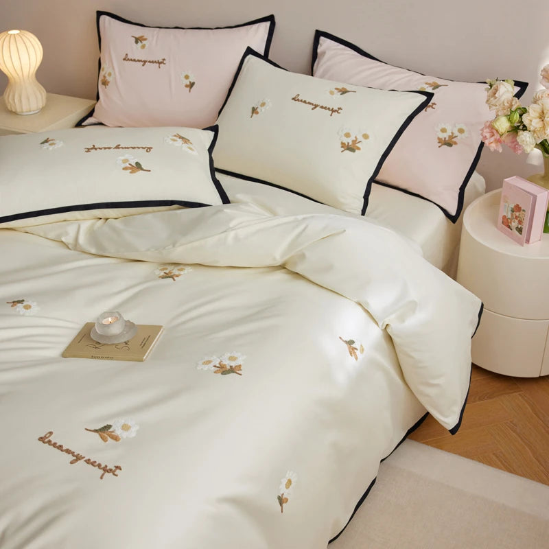 Neatly made bed with white bedding and embroidered designs in a bedroom setting.