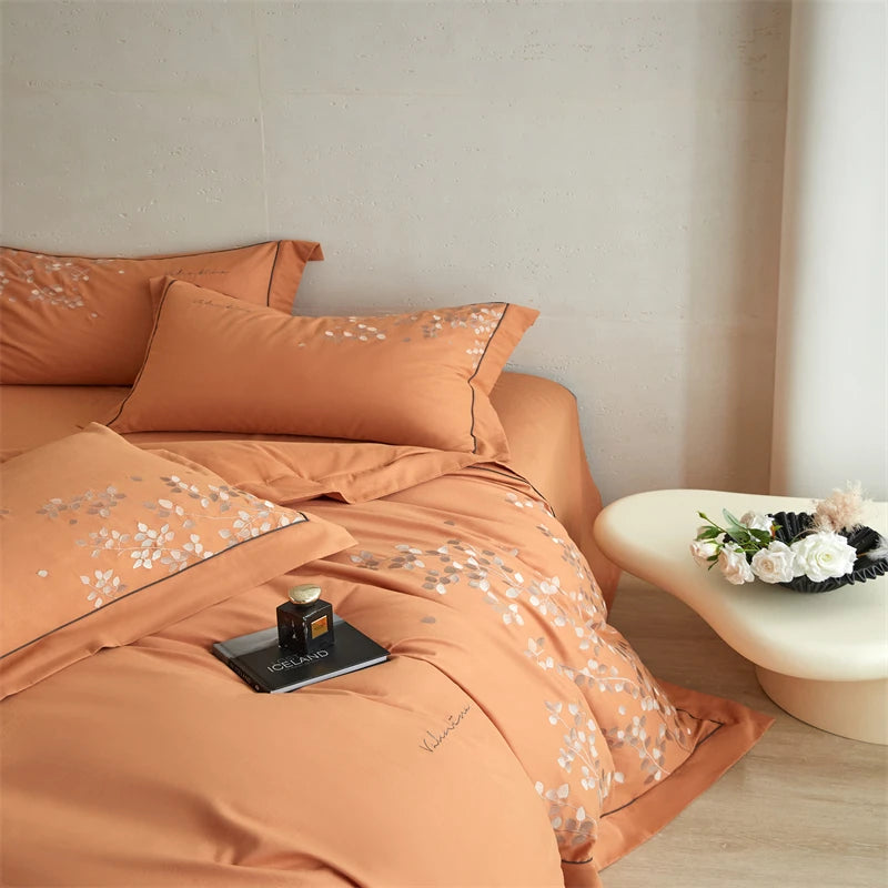 Orange bedding set with floral patterns on a bed in a bedroom setting.