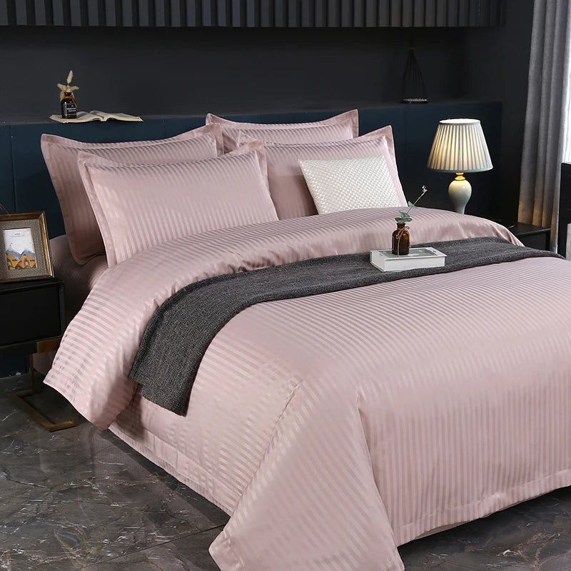Pink bedding set on a bed in a bedroom with a lamp and decor items.