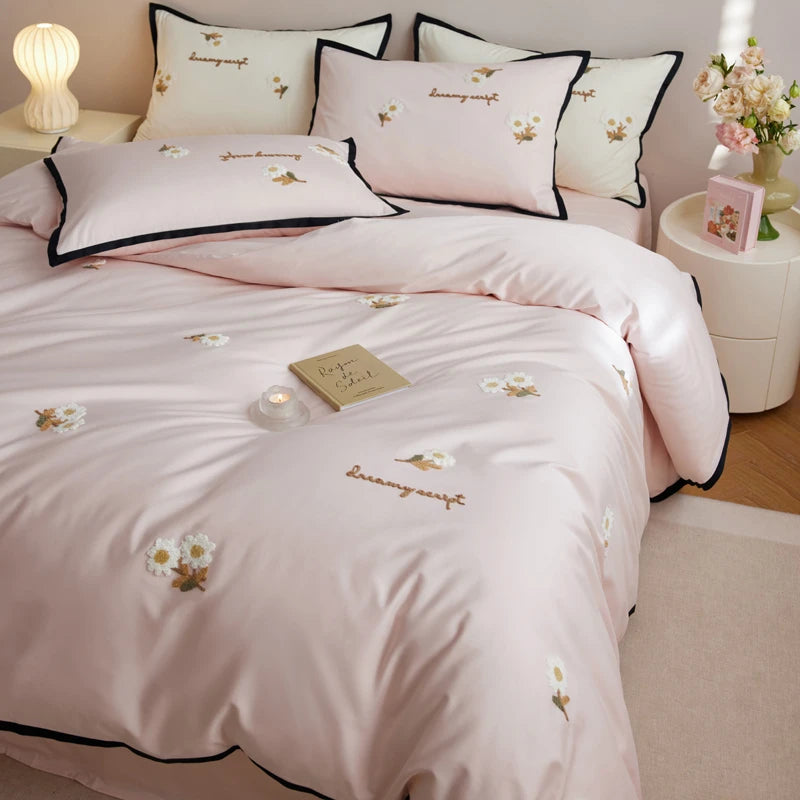 Pink bedding set with floral embroidery in a bedroom setting