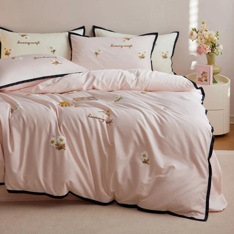 Pink bedding set with floral embroidery on a bed in a bedroom.
