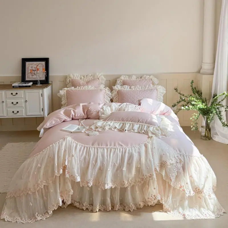 Pink ruffled bedding set on a bed in a bedroom with a side table and plant.