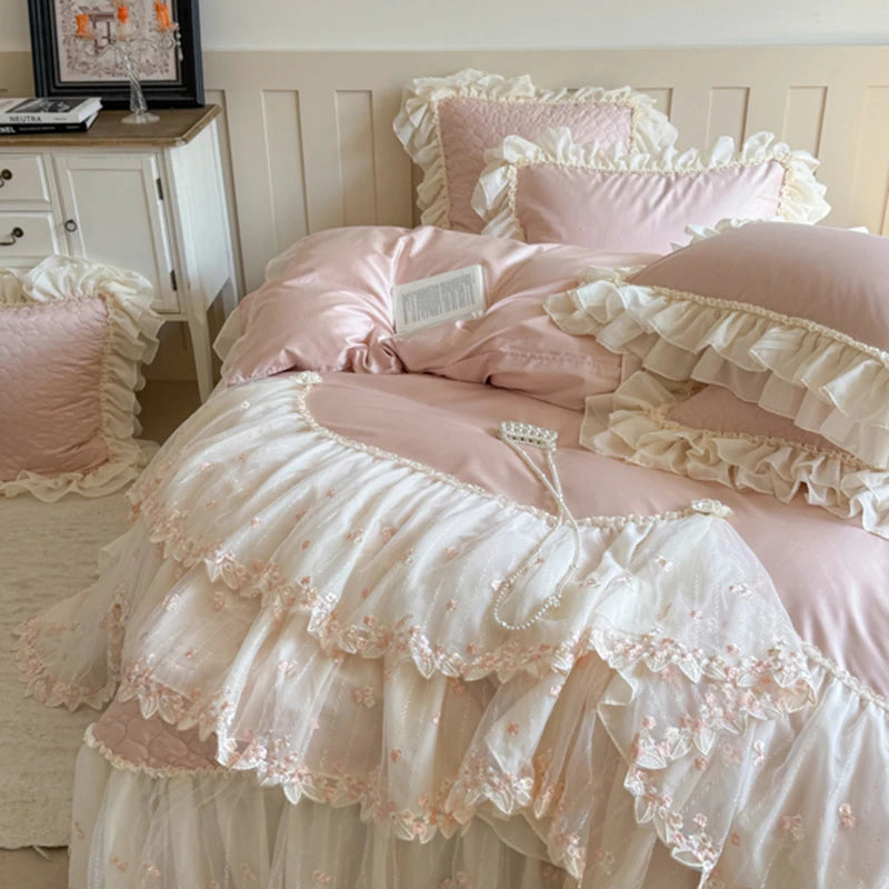 Pink ruffled bedding set on a bed with matching pillows.