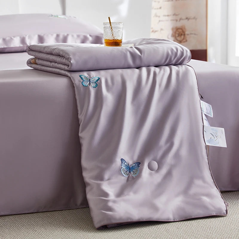 Purple bedding set with butterfly designs on a bed in a bedroom setting.