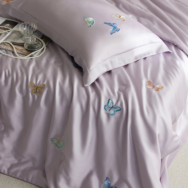 Purple bedding set with embroidered butterflies on a bed.