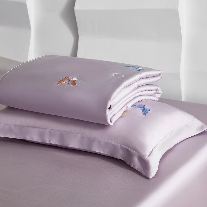 Purple satin pillowcases with floral embroidery on a light lilac background