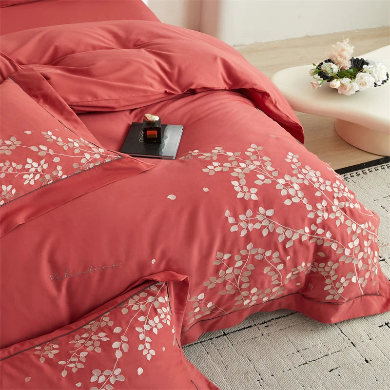 Red floral-patterned bedding set on a bed with a side table in the background.