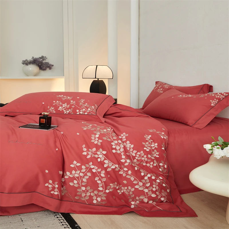 Red floral bedspread on a bed in a bedroom setting with decor elements.
