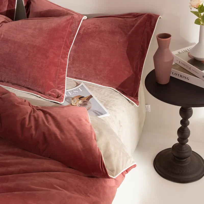 Rust velvet pillows on a bed with a side table and books in the background