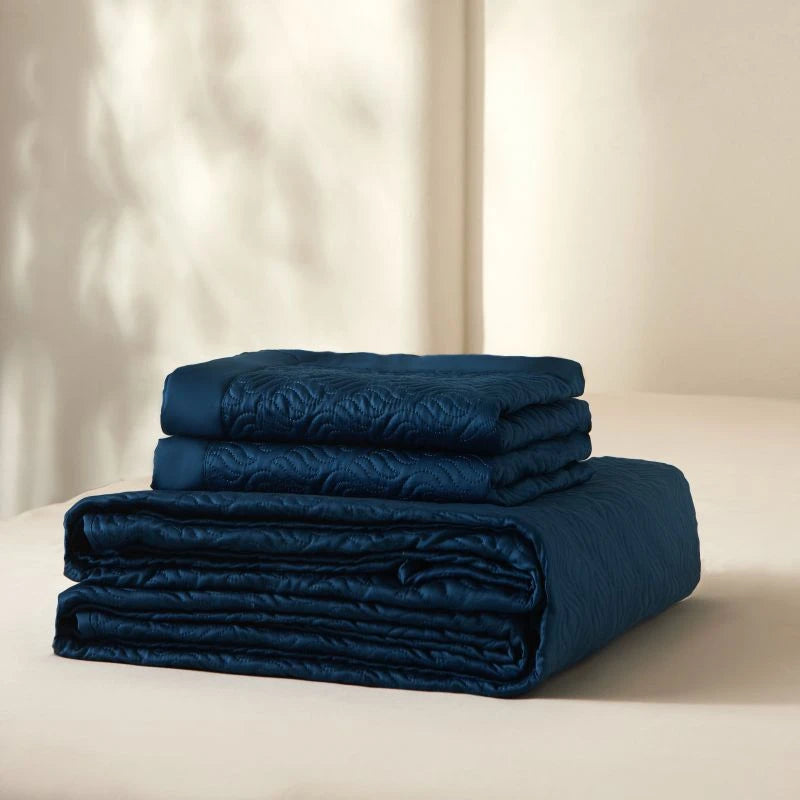 Stack of blue folded bedding set on a neutral background