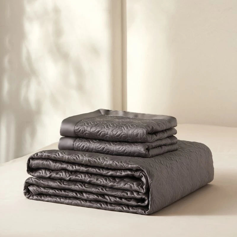 Stack of folded gray bedding set on a light background
