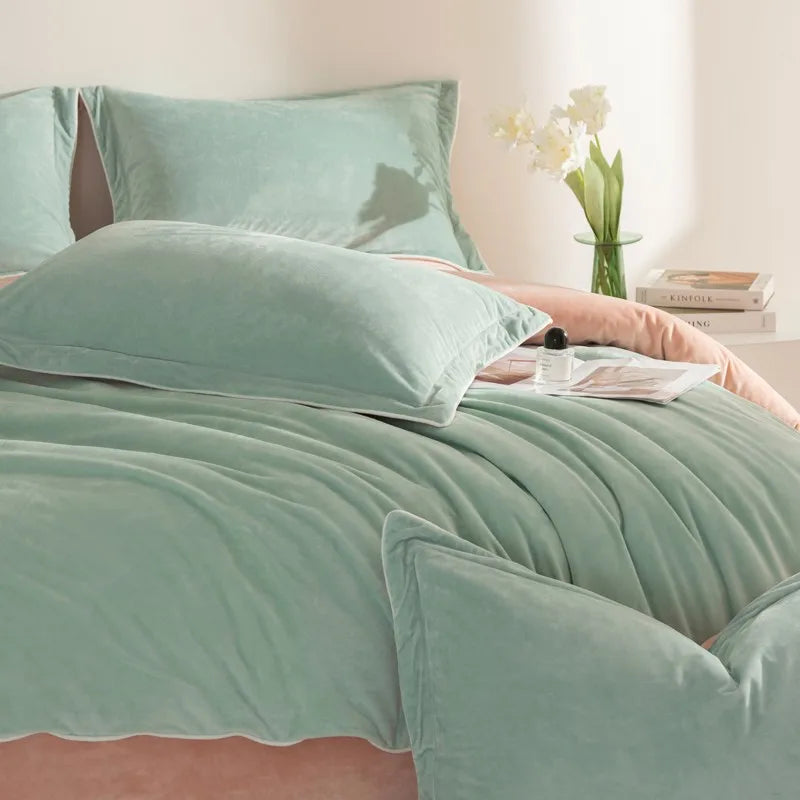 Teal bedding set on a bed with pillows and a vase of flowers in the background.