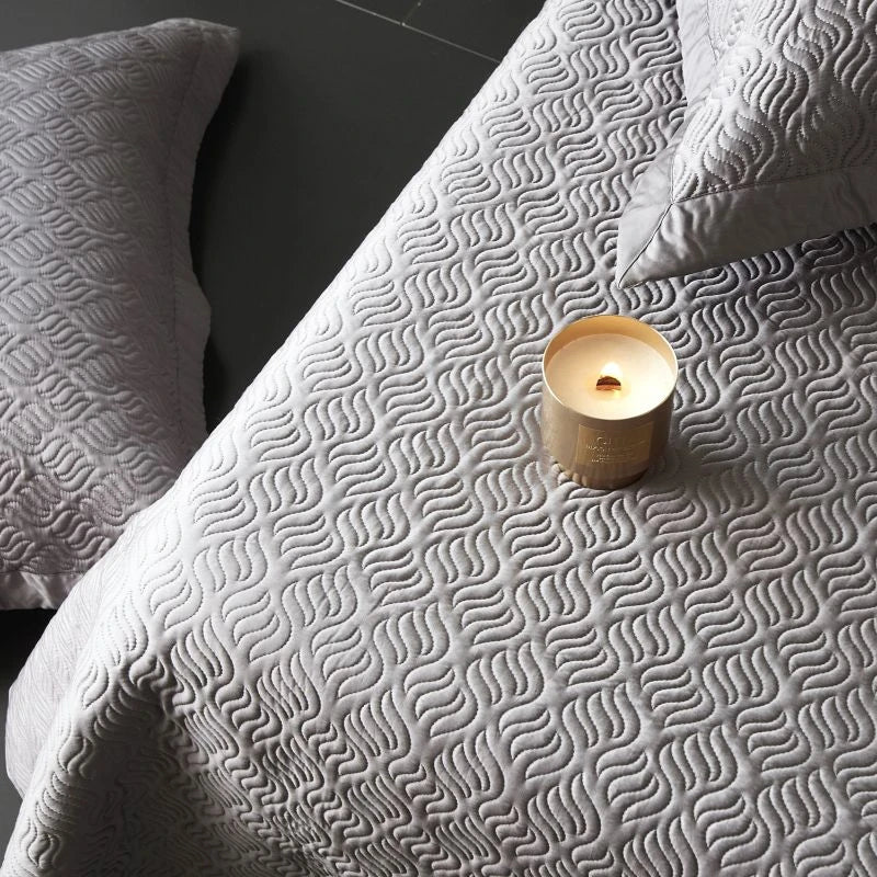 Textured gray blanket with a candle on a dark surface