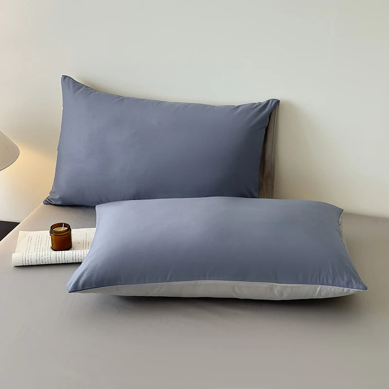 Two gray pillows on a bed with a minimal background
