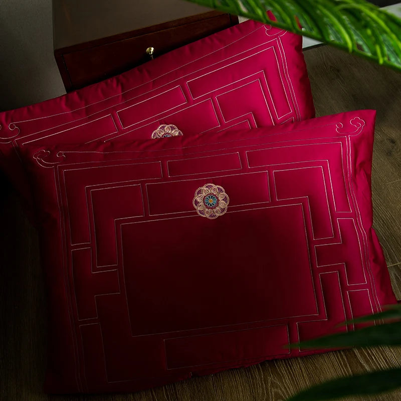 Two red embroidered pillows with decorative buttons on a wooden surface.