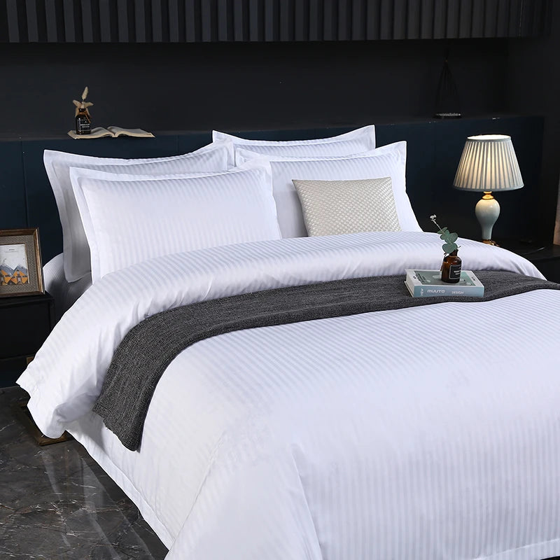 White bedding set on a bed with decorative pillows and a lamp in the background.