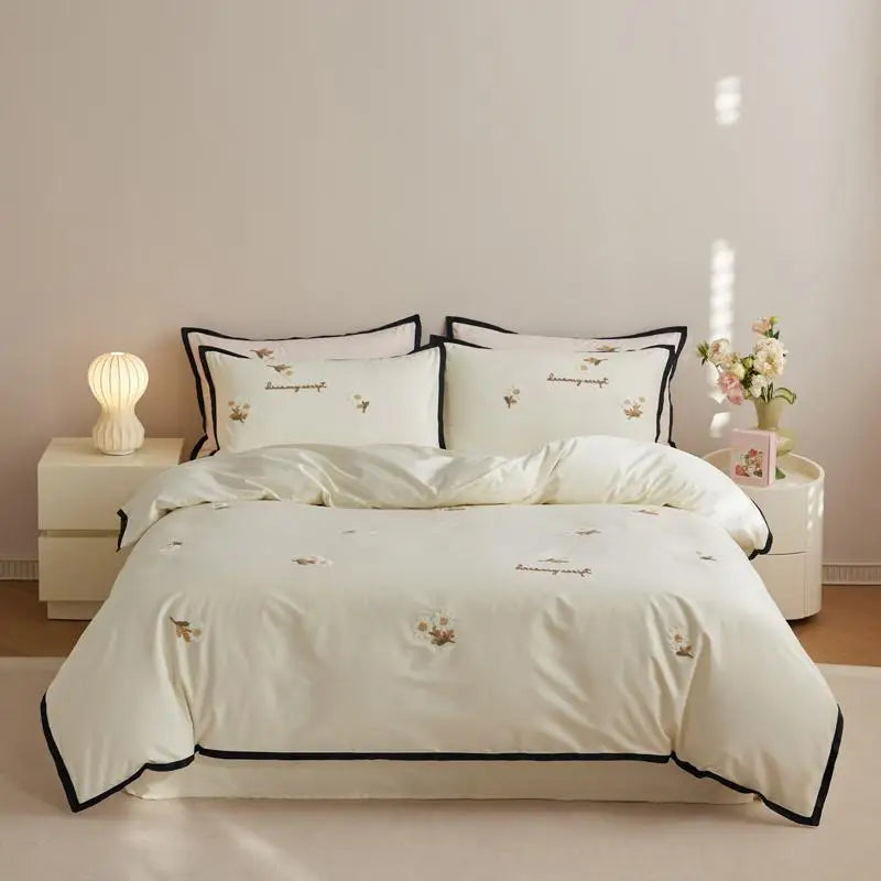 White bedding set with black trim on a bed in a bedroom setting.
