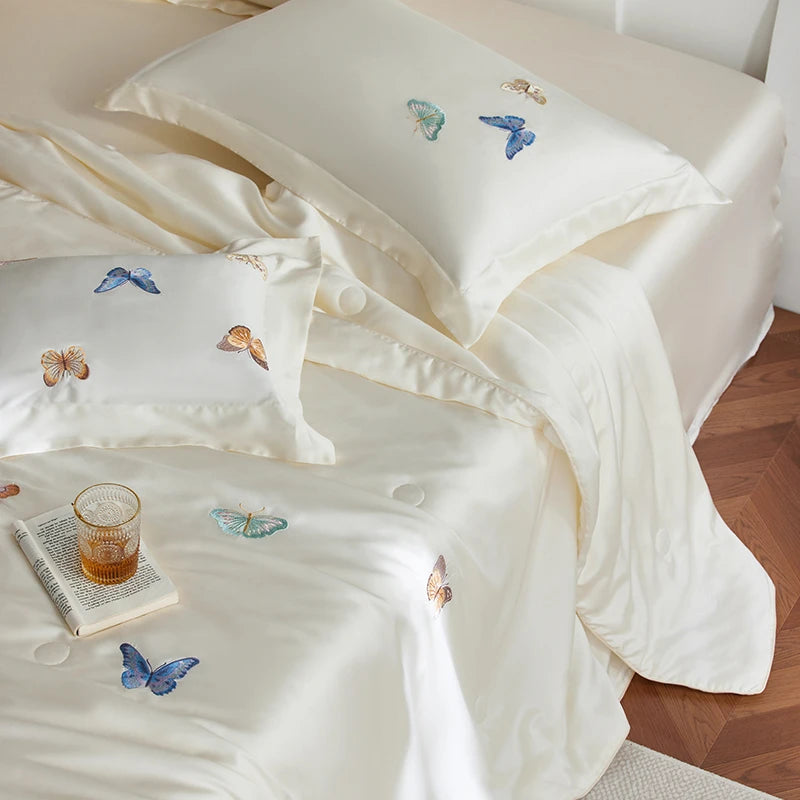 White bedding set with embroidered butterflies on a bed.