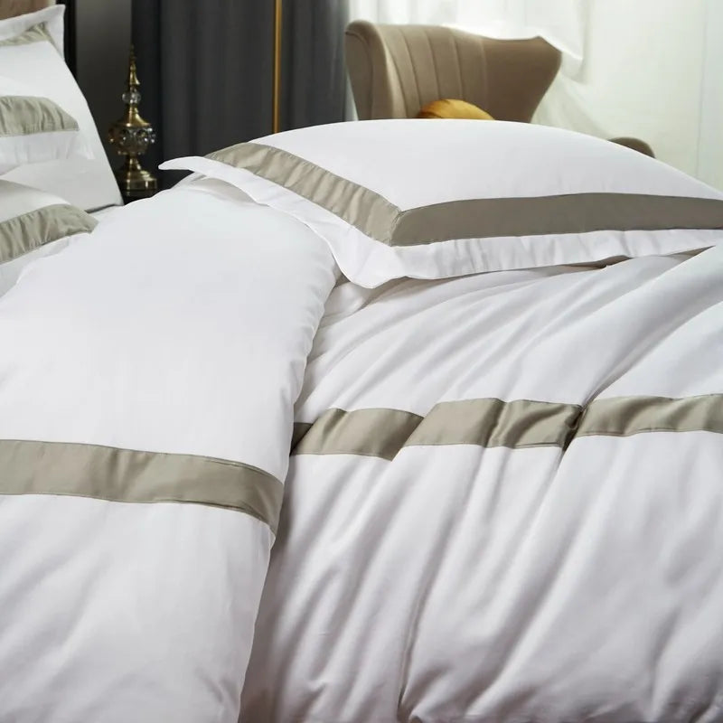 White bedding set with gray stripes on a bed in a bedroom setting.